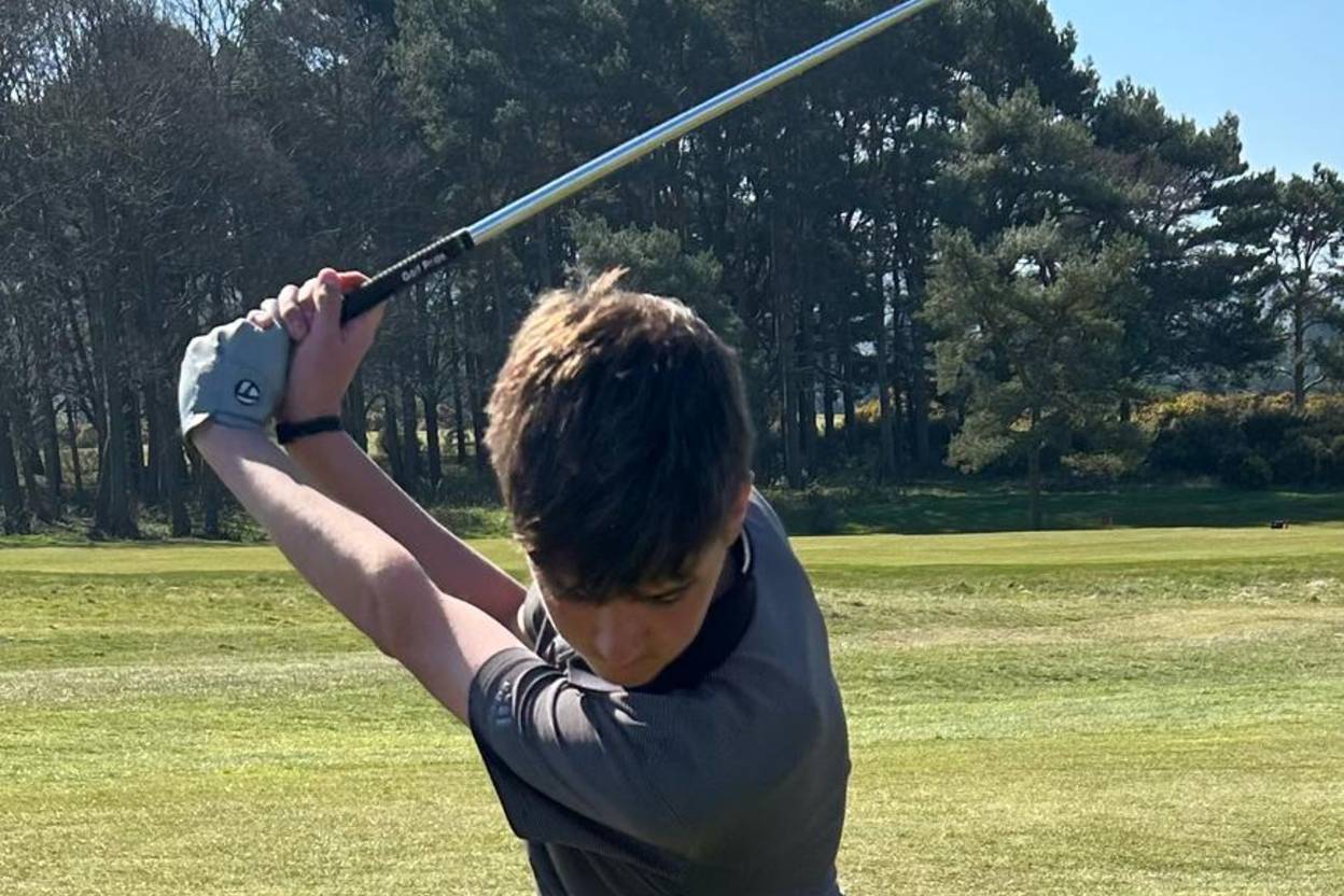 Alfie Daisy, Welsh Junior Golfer, wearing an AV Edge Legend black wristband during a dynamic, full golf swing on a course, validating the performance technology for competitive play