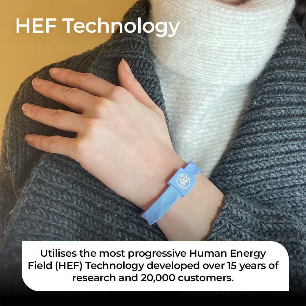 A close-up of a person wearing the AV Edge Advanced Sky Blue frequency wristband over a grey knitted sweater, showcasing the geometric HEF Technology design that might support improved cellular energy, focus, and balance as a stylish, non-magnetic wellness accessory.