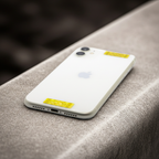 A white phone lying on a stone surface, featuring two yellow AV Edge Cell Phone Protect Filters applied to the back. This EF Technology acts as a signal modulator that might reduce phone radiation without losing signal, potentially helping to reduce phone-induced tech fatigue and brain fog.