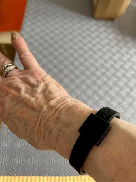 Close-up of valued customer Judith wearing her AV Edge Legend Noir frequency wristband, demonstrating a discreet lifestyle look that might help with balance and may support improved energy levels and fatigue management as part of a daily health and well-being routine.