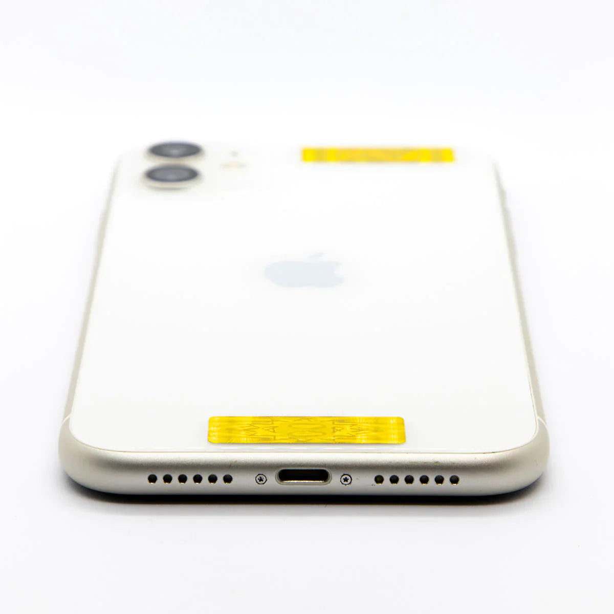 A low-angle, close-up of a white phone on a plain white background, showing two yellow AV Edge Cell Phone Protect Filters placed at the top and bottom of the device's rear casing. This placement demonstrates how the EF Technology may provide a biological filter for mobile data and natural EMF protection without blocking the signal.